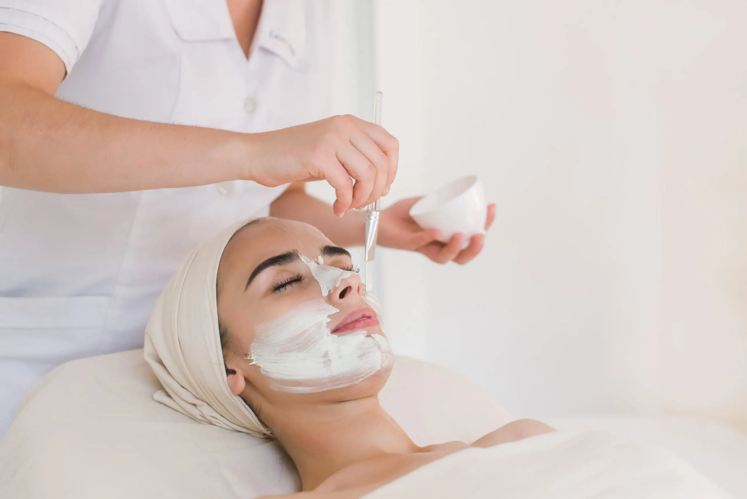 a woman lying down with a white mask on her face Facials and Packages in Hamilton, NJ